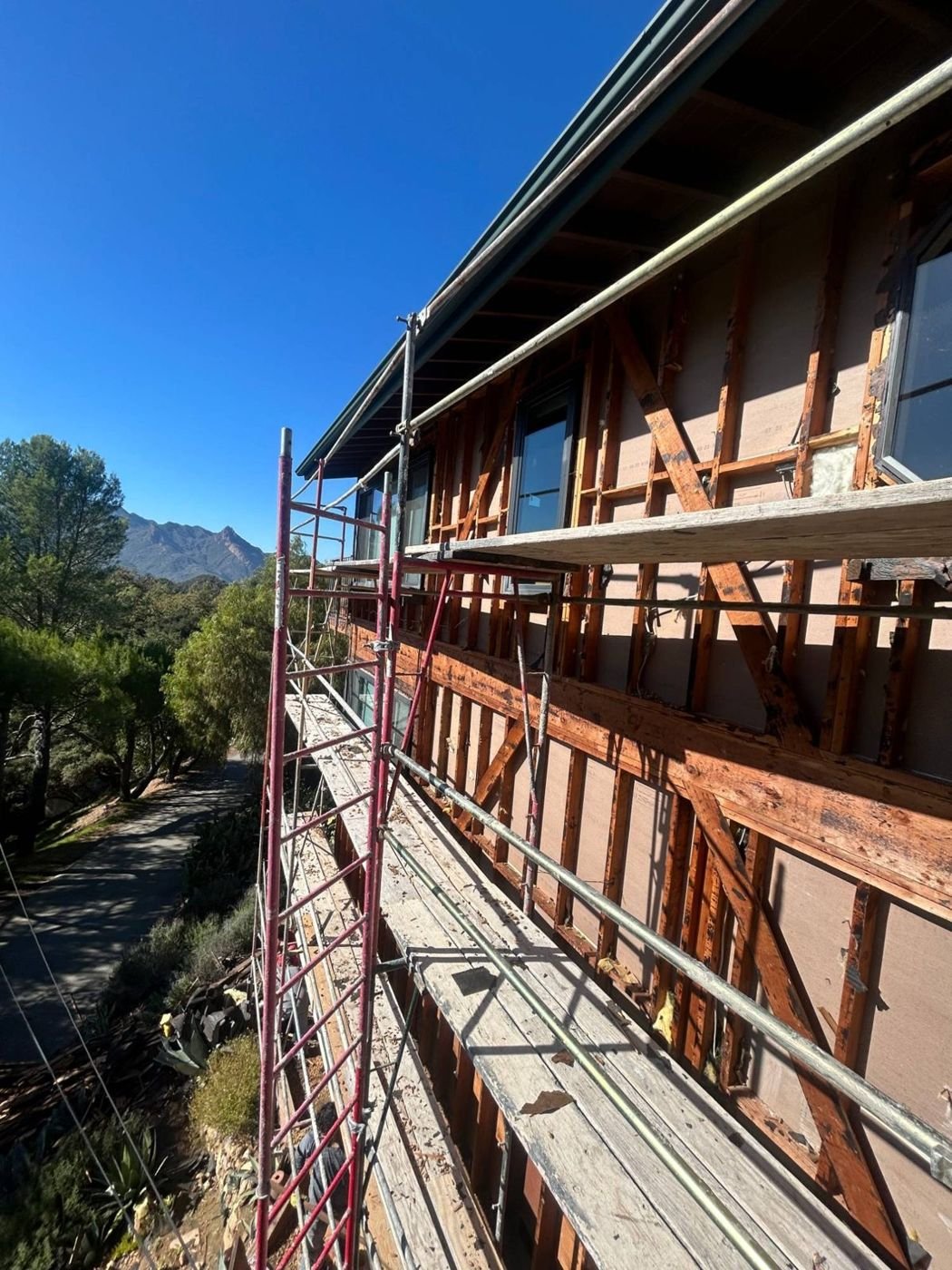 Siding tear-off: framing and sheathing exposed and checked for dry rot before the new weather barrier