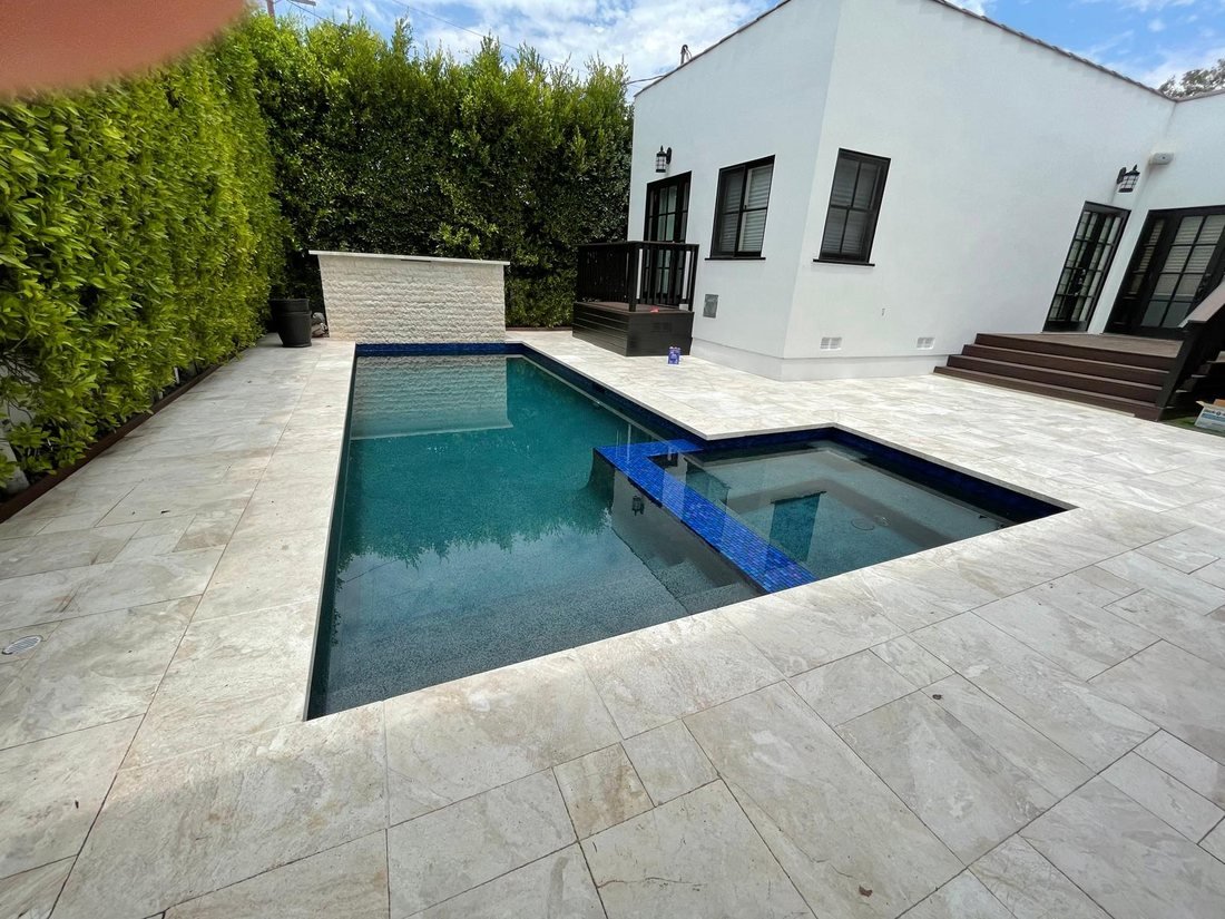 Large pool with raised spa, stone spillway, and travertine decking — Right Image Builders